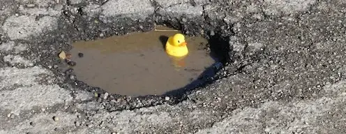 pothole with water and a rubber duckey in the middle of it