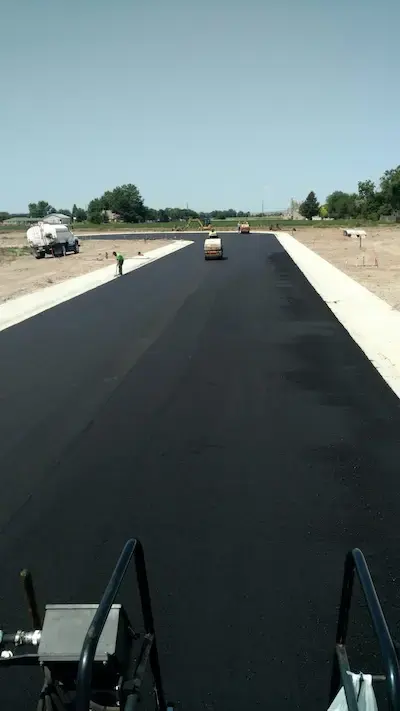 Rolling the asphalt of a freshly paved subdivision road.